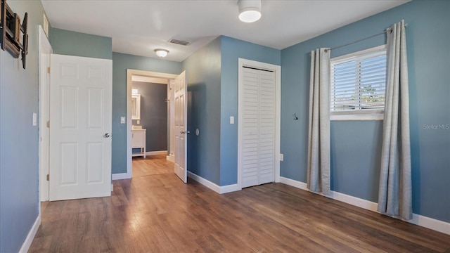 unfurnished bedroom with dark wood-type flooring and a closet