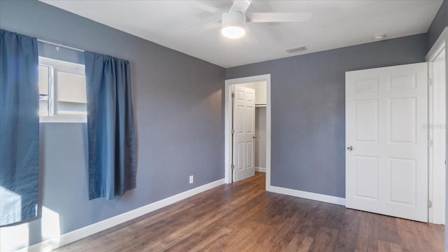 unfurnished bedroom with a closet, dark hardwood / wood-style floors, and ceiling fan