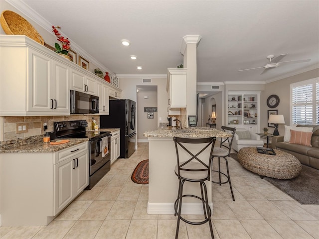 kitchen featuring kitchen peninsula, ceiling fan, black appliances, white cabinets, and a breakfast bar area