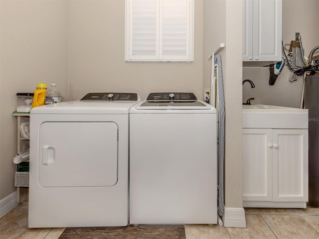 laundry room featuring washer and clothes dryer, light tile patterned flooring, and cabinets