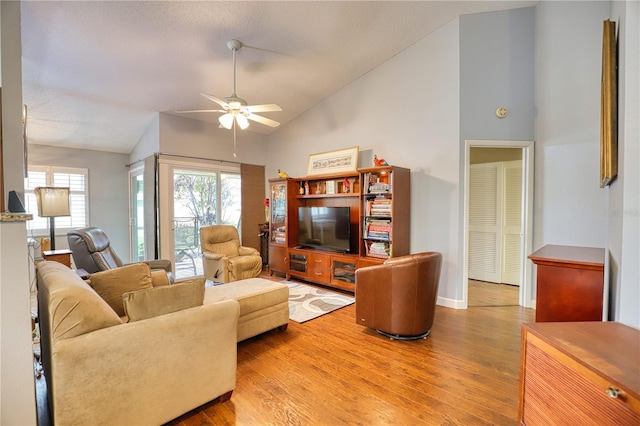 living room with ceiling fan, light hardwood / wood-style flooring, and lofted ceiling