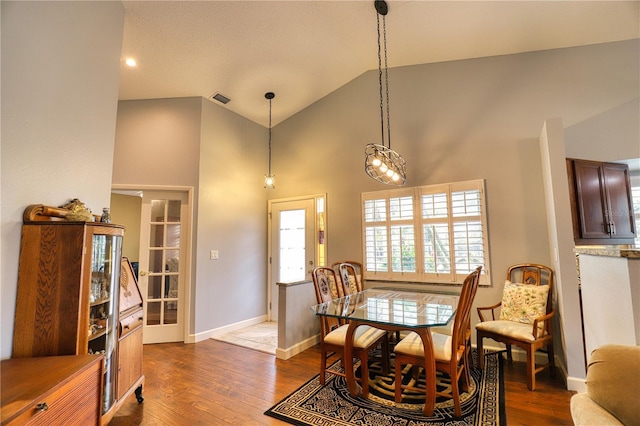 dining space featuring high vaulted ceiling and wood-type flooring