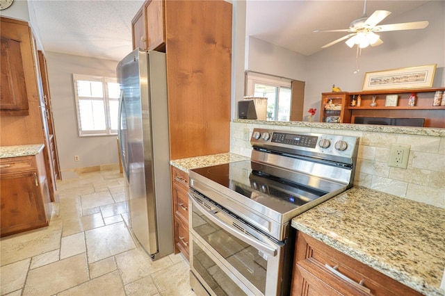 kitchen featuring a textured ceiling, plenty of natural light, light stone countertops, and stainless steel appliances