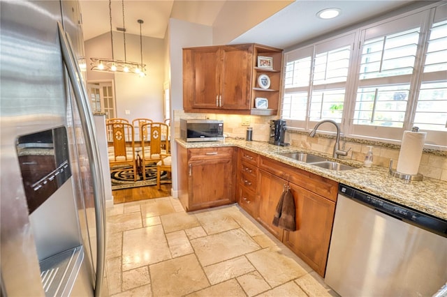 kitchen with pendant lighting, backsplash, sink, vaulted ceiling, and appliances with stainless steel finishes