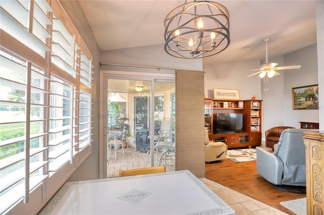 dining room with ceiling fan with notable chandelier, lofted ceiling, and light wood-type flooring