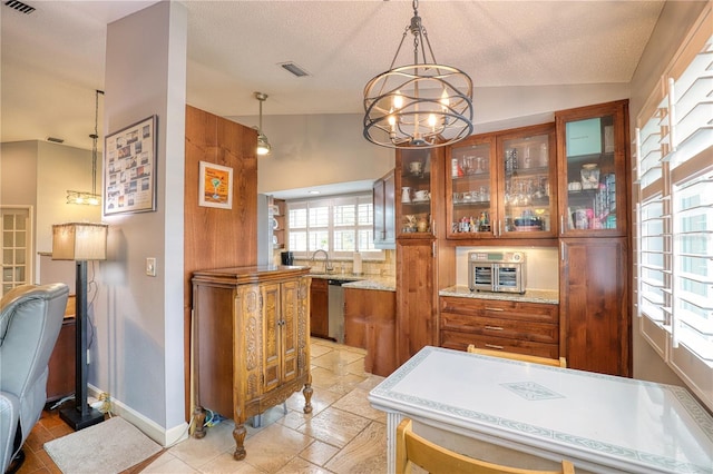 dining area featuring a chandelier, a textured ceiling, vaulted ceiling, and sink