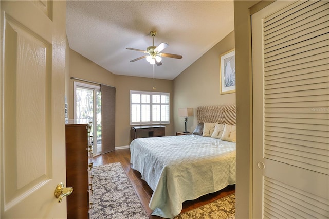 bedroom with a textured ceiling, ceiling fan, lofted ceiling, and hardwood / wood-style flooring