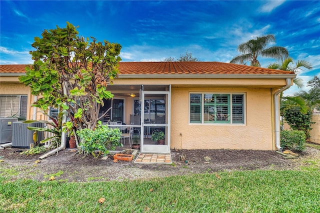 back of property featuring a lawn, central AC, and a sunroom