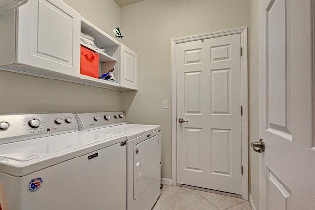 washroom featuring washer and dryer, light tile patterned flooring, and cabinets