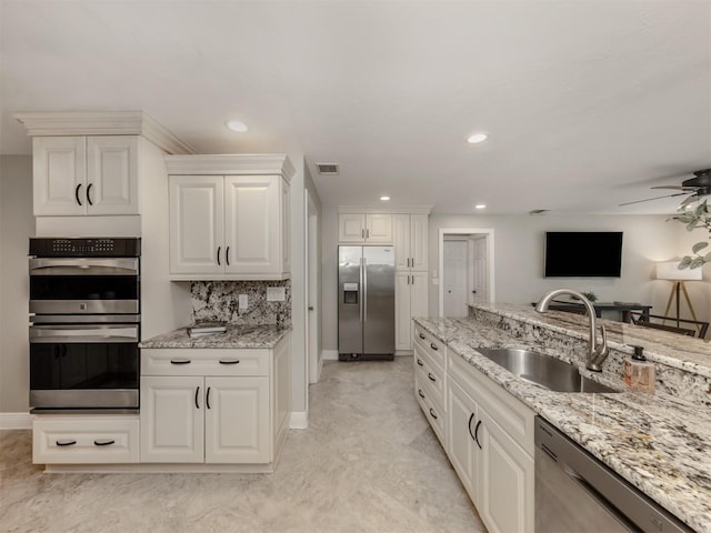 kitchen with white cabinetry, sink, light stone countertops, tasteful backsplash, and appliances with stainless steel finishes