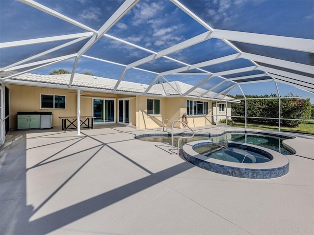 view of pool with an in ground hot tub, glass enclosure, and a patio area