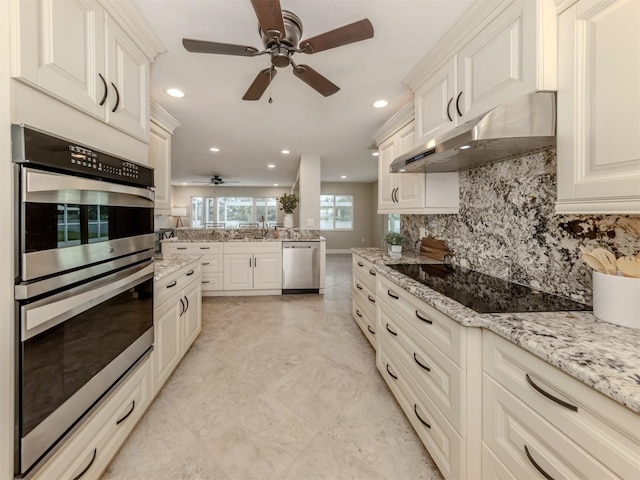 kitchen featuring tasteful backsplash, white cabinetry, stainless steel appliances, and light stone counters