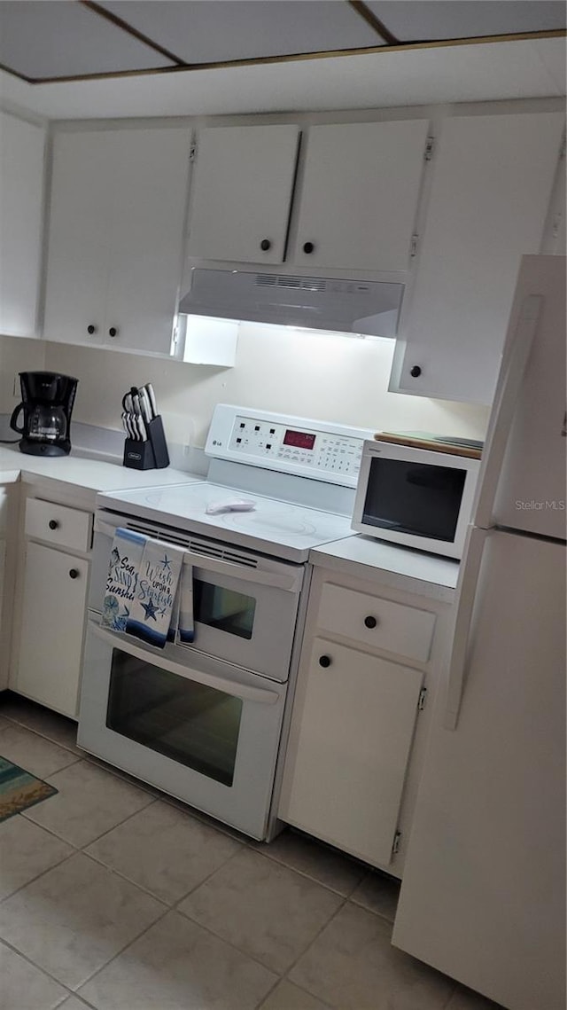 kitchen with light tile patterned floors, white cabinets, and white appliances