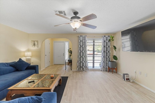 living room featuring ceiling fan, light hardwood / wood-style floors, and a textured ceiling