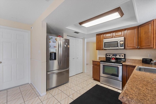 kitchen featuring appliances with stainless steel finishes, light tile patterned floors, and sink