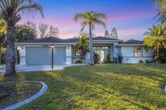 ranch-style home featuring a lawn and a garage