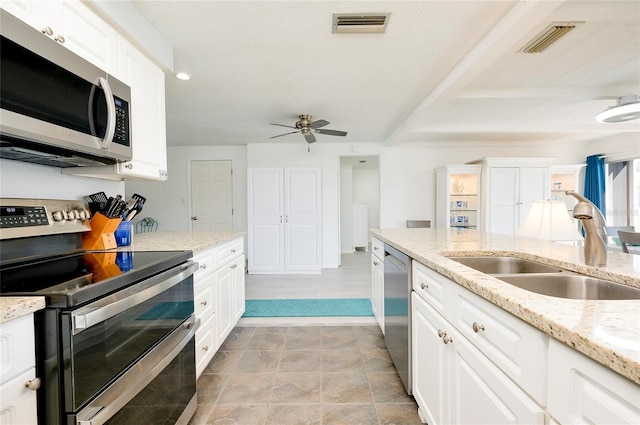 kitchen with appliances with stainless steel finishes, sink, white cabinetry, and light stone counters