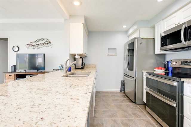 kitchen with white cabinets, stainless steel appliances, light stone countertops, and sink