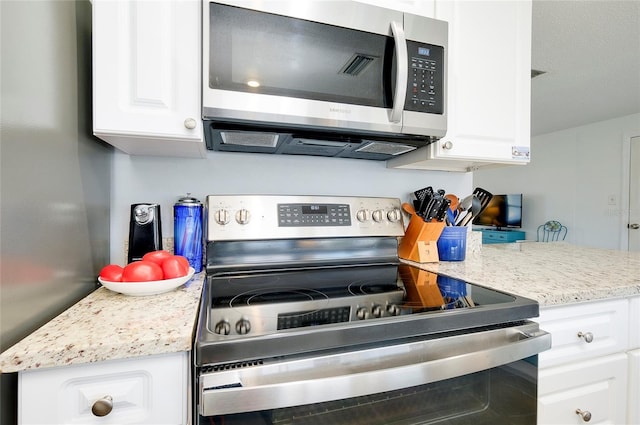 kitchen featuring light stone countertops, white cabinets, and stainless steel appliances