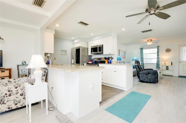 kitchen with sink, light stone counters, kitchen peninsula, white cabinets, and appliances with stainless steel finishes