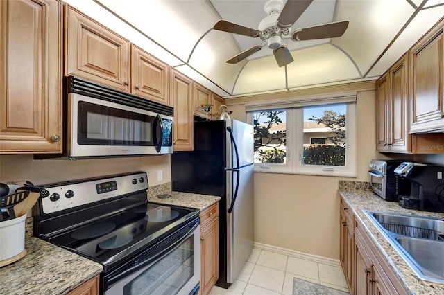 kitchen featuring light stone counters, stainless steel appliances, ceiling fan, sink, and light tile patterned floors