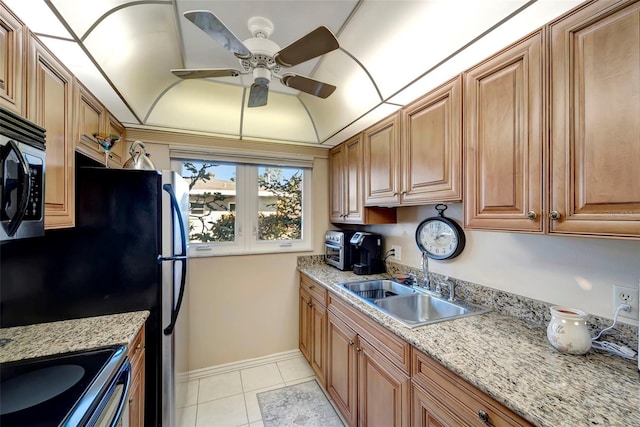 kitchen with light tile patterned flooring, light stone counters, ceiling fan, and sink