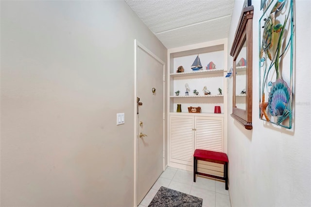 entryway with light tile patterned floors, a textured ceiling, and built in features