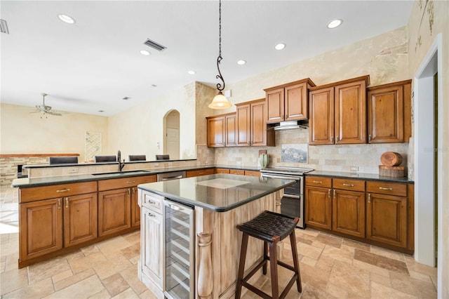 kitchen featuring hanging light fixtures, sink, appliances with stainless steel finishes, kitchen peninsula, and beverage cooler