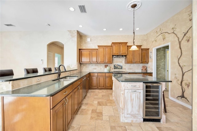 kitchen with a kitchen bar, sink, a center island, wine cooler, and hanging light fixtures