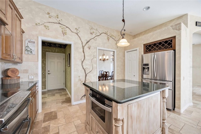 kitchen with a center island, stainless steel appliances, a notable chandelier, dark stone countertops, and decorative light fixtures