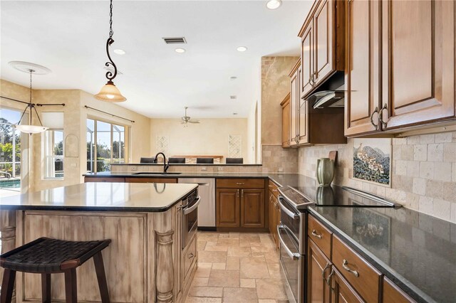 kitchen featuring sink, stainless steel appliances, tasteful backsplash, decorative light fixtures, and a kitchen bar