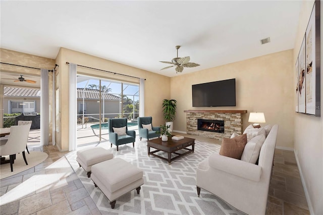 living room with ceiling fan and a fireplace