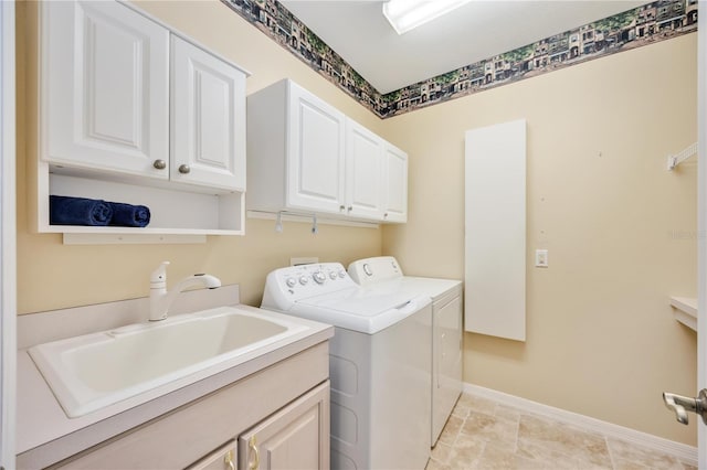 clothes washing area featuring washer and clothes dryer, cabinets, and sink