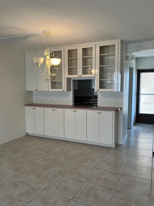 kitchen featuring light tile patterned flooring, white cabinetry, decorative light fixtures, a textured ceiling, and a notable chandelier