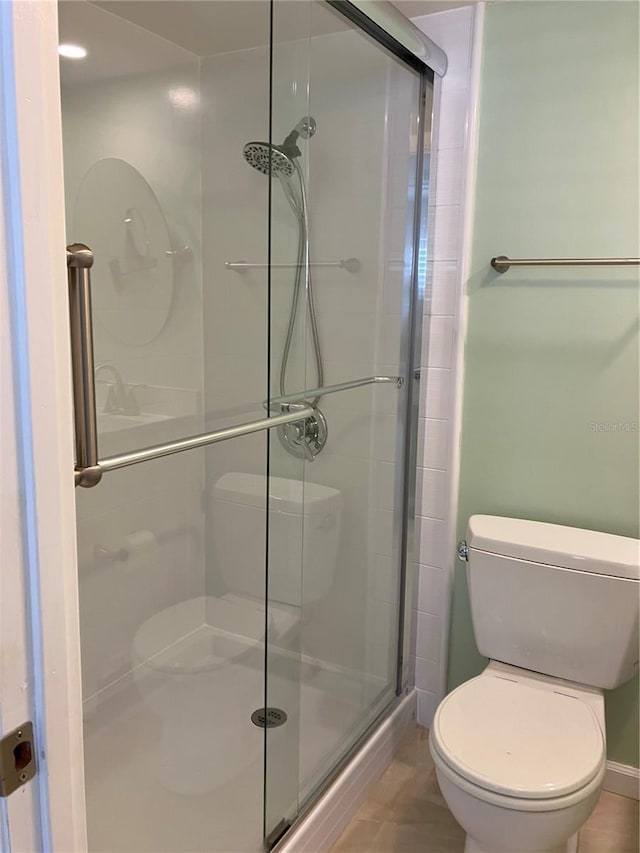 bathroom featuring tile patterned floors, toilet, and walk in shower