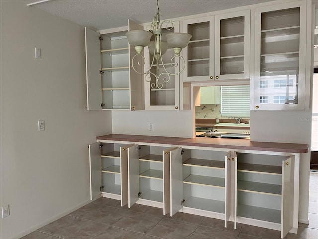 unfurnished dining area with a notable chandelier, tile patterned floors, sink, and a textured ceiling