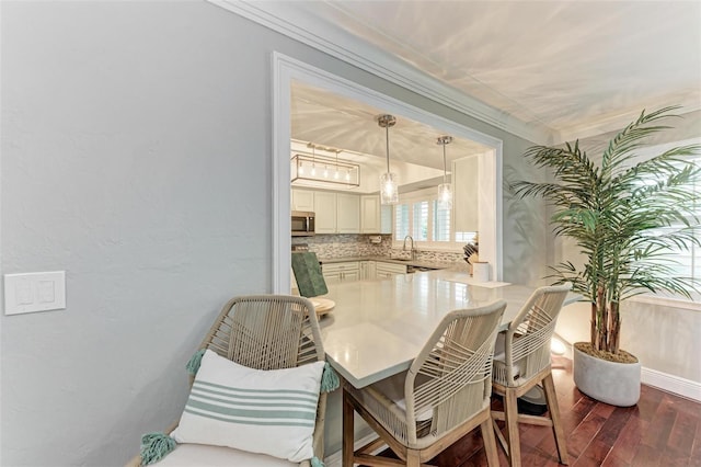 dining room featuring dark wood-type flooring, sink, and crown molding