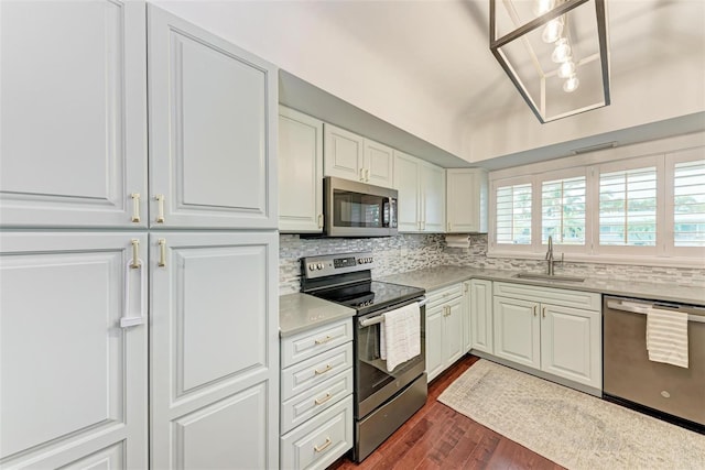 kitchen with tasteful backsplash, sink, white cabinetry, appliances with stainless steel finishes, and dark wood-type flooring