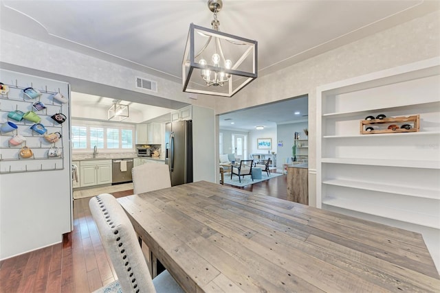 dining space with sink, dark hardwood / wood-style flooring, and a notable chandelier