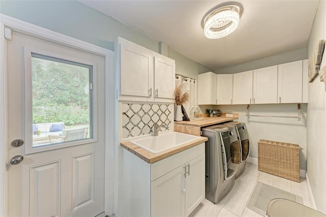 laundry room with washer and clothes dryer, sink, and cabinets