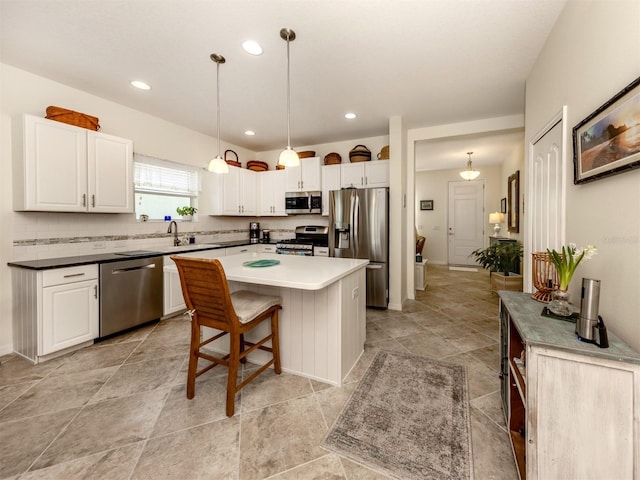 kitchen featuring a center island, white cabinetry, hanging light fixtures, and appliances with stainless steel finishes