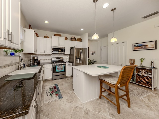 kitchen with stainless steel appliances, hanging light fixtures, a center island, sink, and white cabinetry