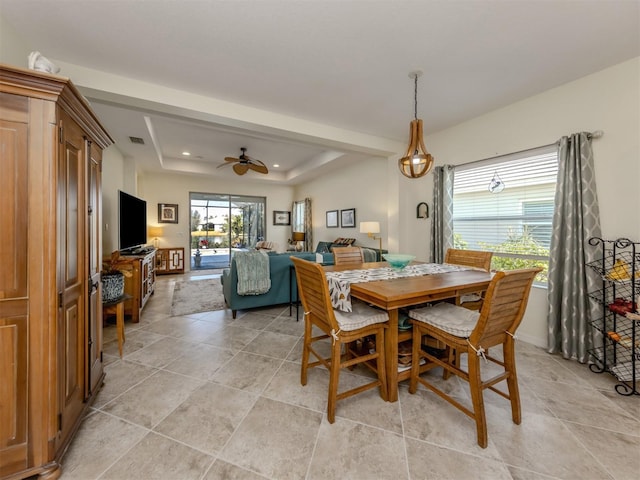 dining room with ceiling fan and a tray ceiling