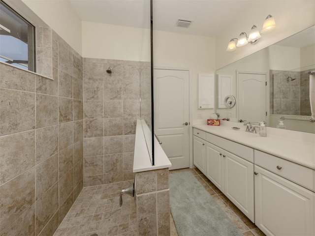 bathroom featuring tiled shower and vanity