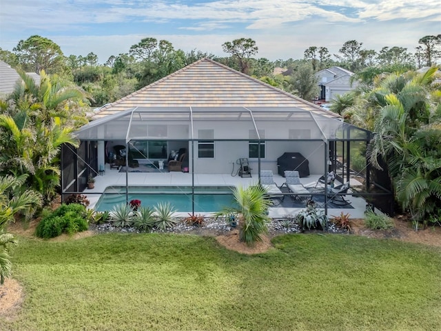 back of house featuring a lanai, a patio area, and a lawn