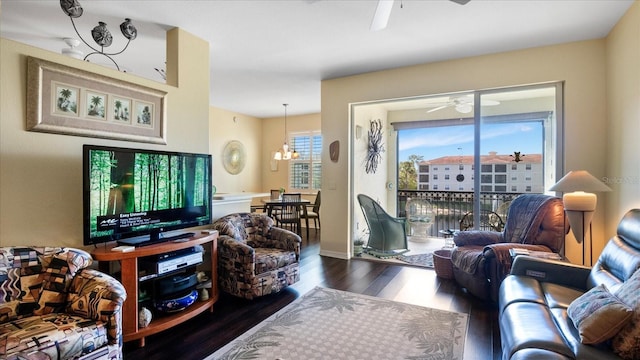 living room with ceiling fan with notable chandelier and dark hardwood / wood-style floors