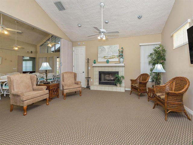 sitting room featuring a tile fireplace, vaulted ceiling, carpet, and a textured ceiling