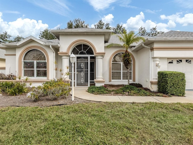 view of exterior entry featuring a garage and a lawn