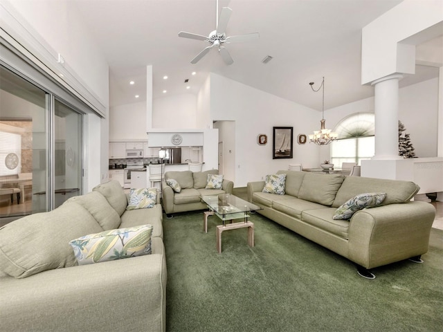 living room featuring high vaulted ceiling, ceiling fan with notable chandelier, decorative columns, and carpet