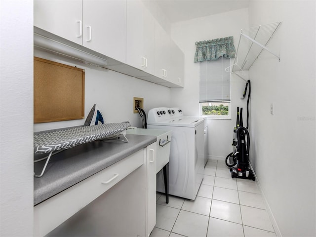 clothes washing area featuring cabinets, light tile patterned flooring, and washing machine and clothes dryer